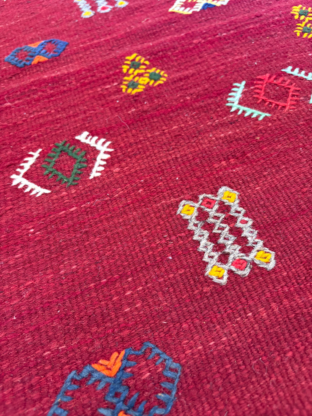 Close-up of handwoven Amazigh motifs on a Moroccan small red wool kilim rug