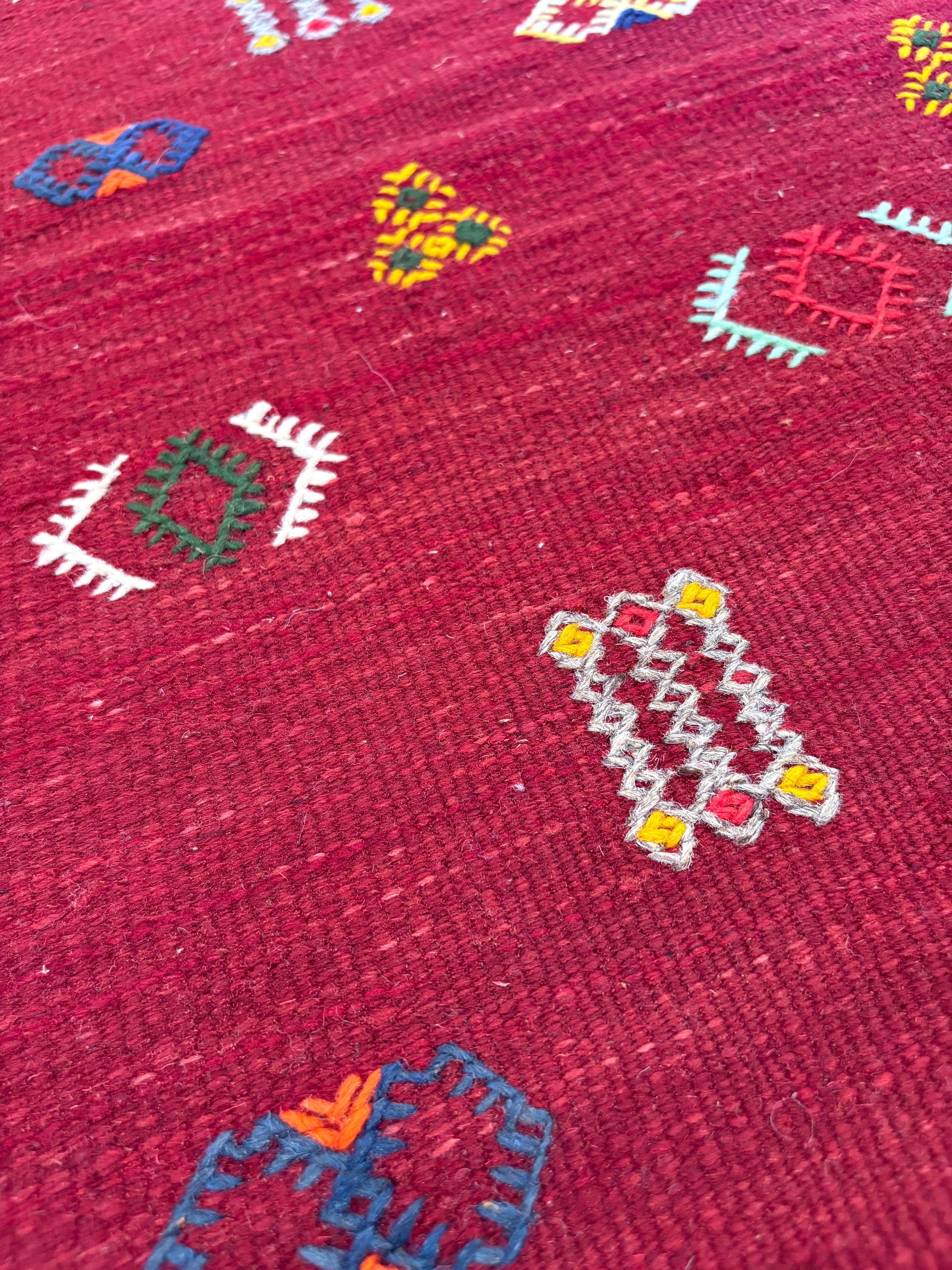 Close-up of handwoven Amazigh motifs on a Moroccan small red wool kilim rug