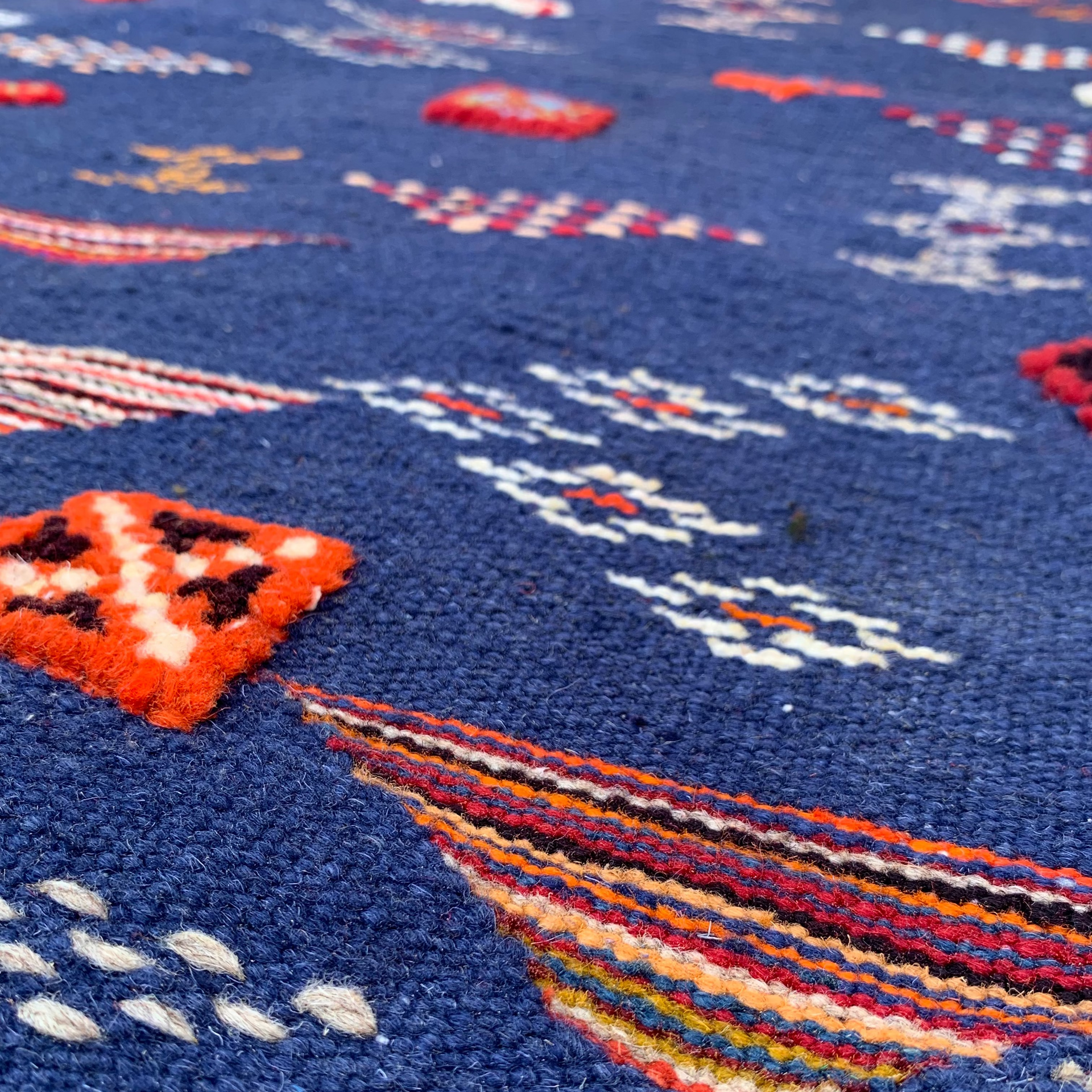 Close-up of a navy blue rug with colorful geometric patterns