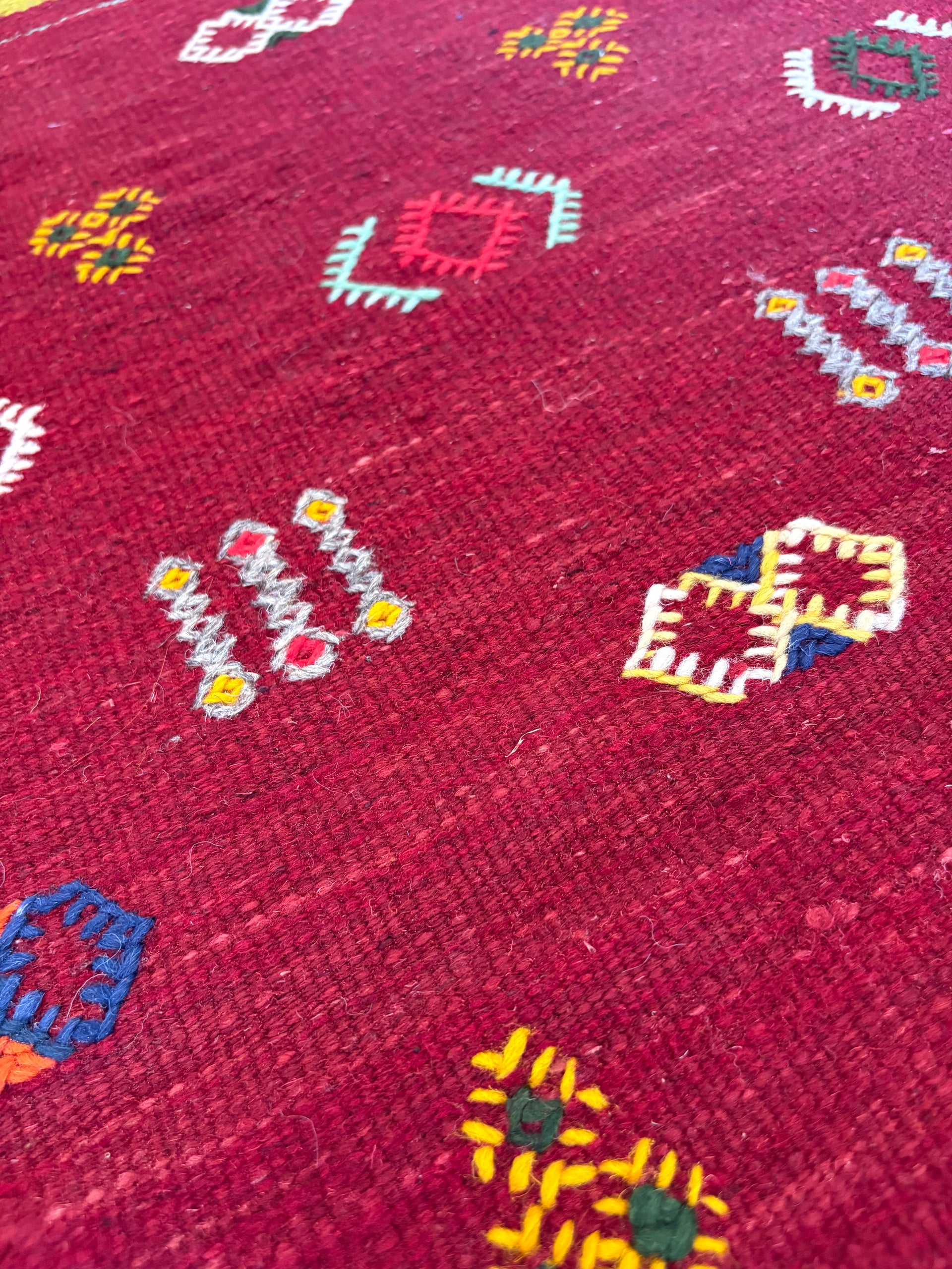 Close-up of handwoven Amazigh motifs on a Moroccan red wool kilim rug