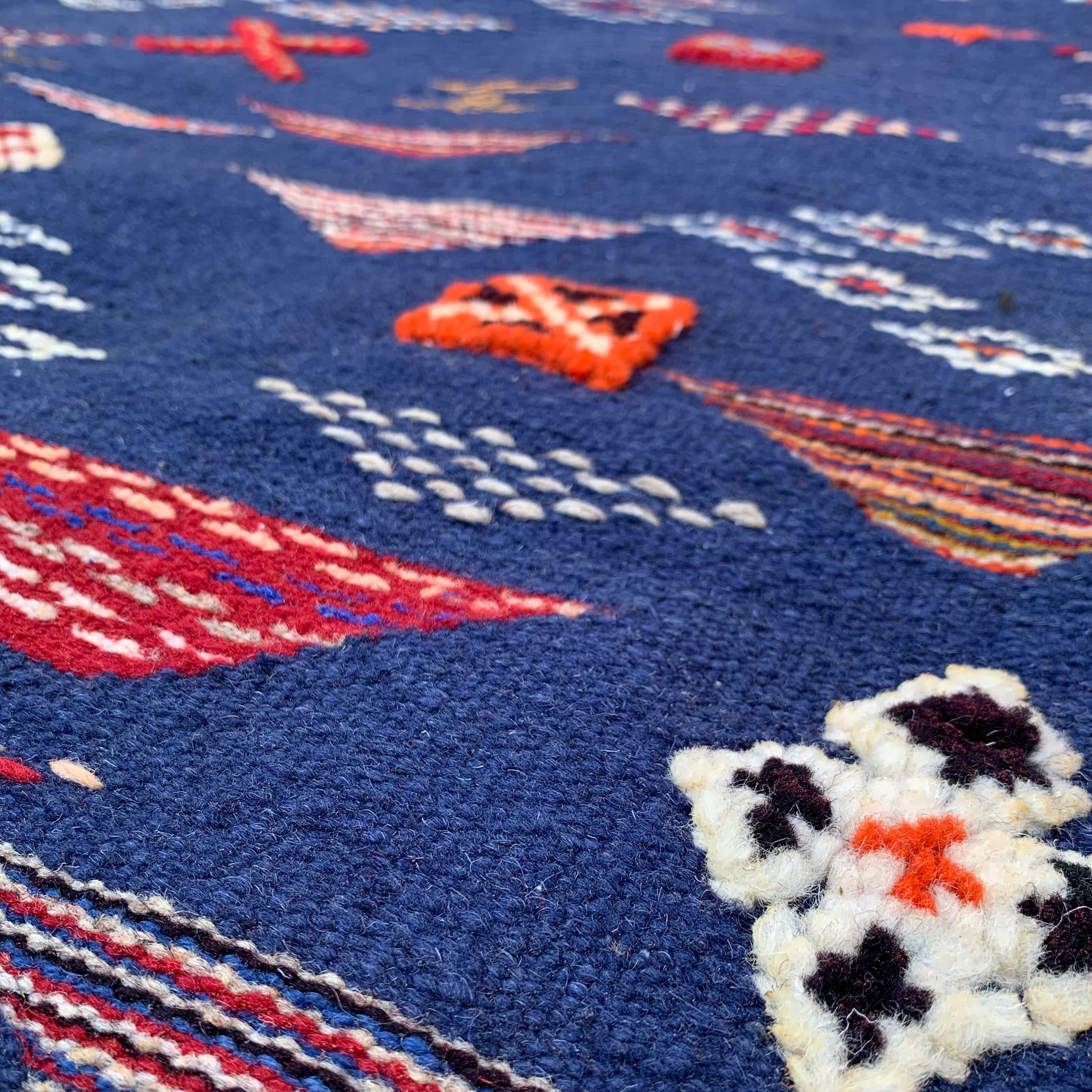 Close-up of a navy blue rug with embroidered patterns and a snowman design.