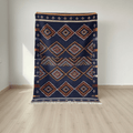 Navy blue patterned rug on a wooden floor with a white wall background
