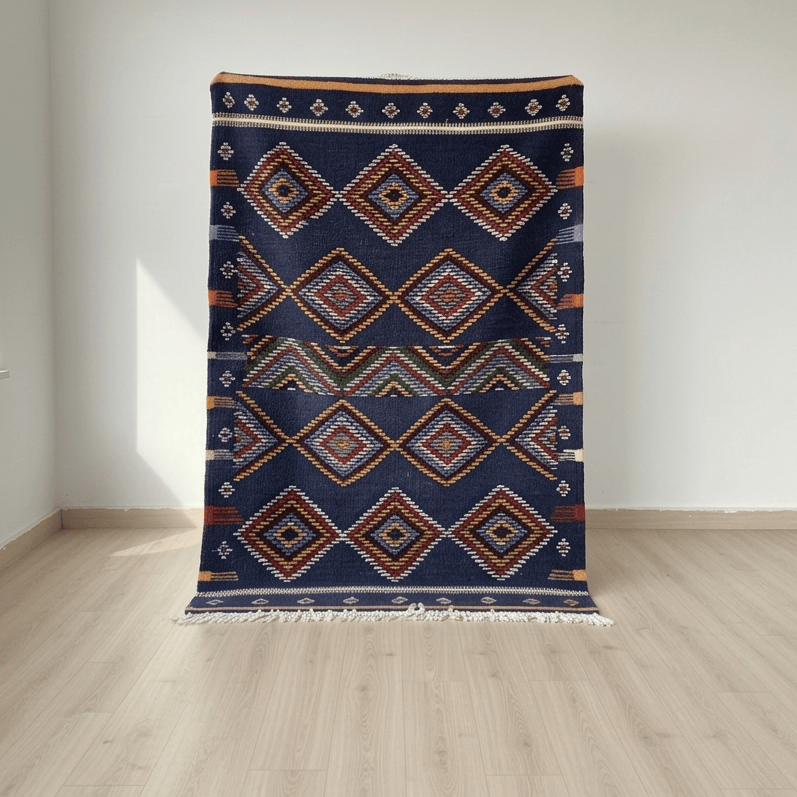 Navy blue patterned rug on a wooden floor with a white wall background