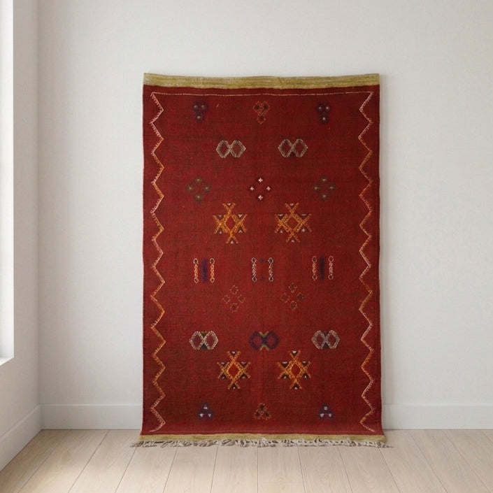 Handwoven Moroccan Berber kilim rug in 100% Atlas Mountain wool with a crimson field and traditional Amazigh symbols, 26 × 39 in (67 × 98 cm).