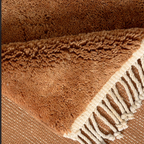 Close-up of caramel Moroccan rug showing medium wool pile, flatweave line and knotted cream fringe