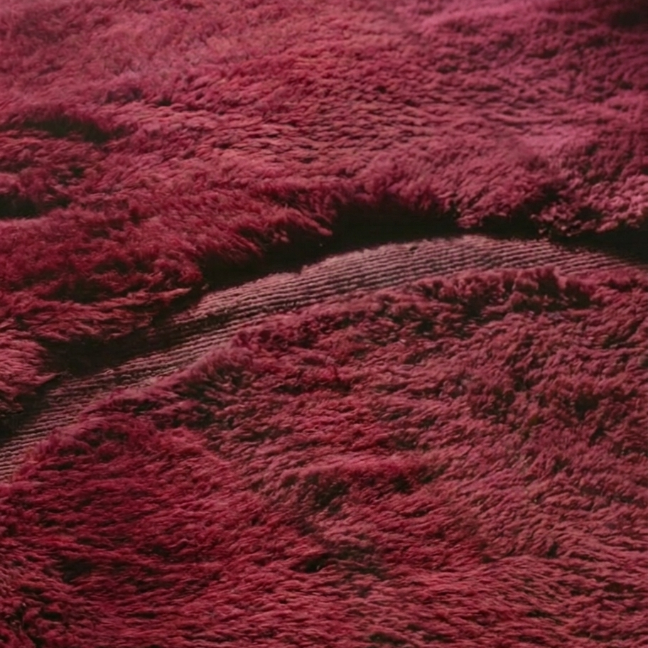 Texture detail — Close-up of a burgundy Moroccan rug showing hand-knotted pile beside flat woven bands