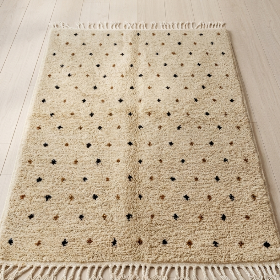 Detail of folded rug edge showing flatwoven back, braided fringe, and diamond motif on backing