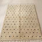 Detail of folded rug edge showing flatwoven back, braided fringe, and diamond motif on backing
