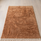 Caramel Beni Mrirt wool rug at the foot of a bed, medium pile with flatweave lines