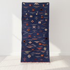 Navy blue rug with geometric pattern on a white floor and background