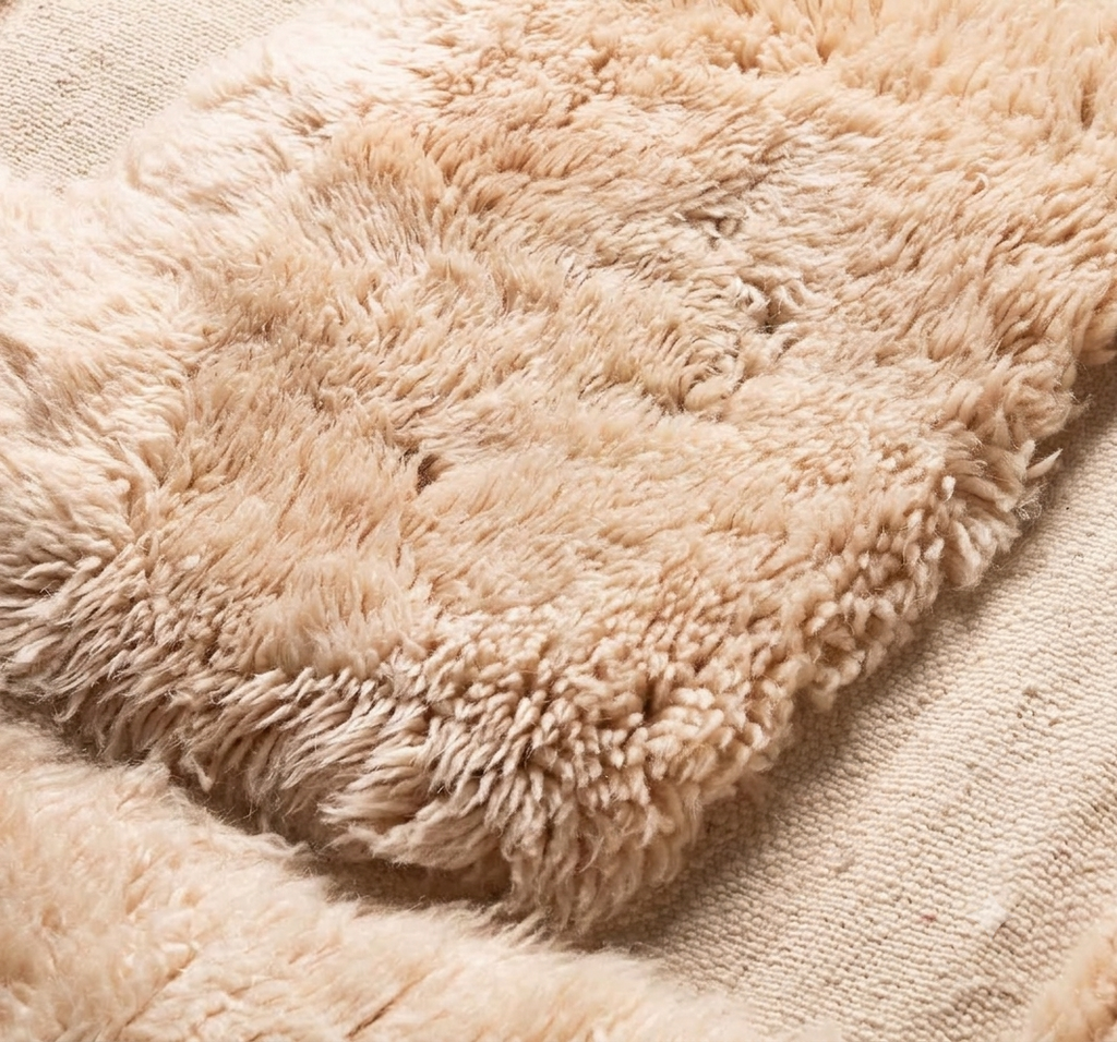 A close-up of a Beni Ourain Moroccan rug in sand wool 118 x 79 in with raised pile blocks on a flatweave ground