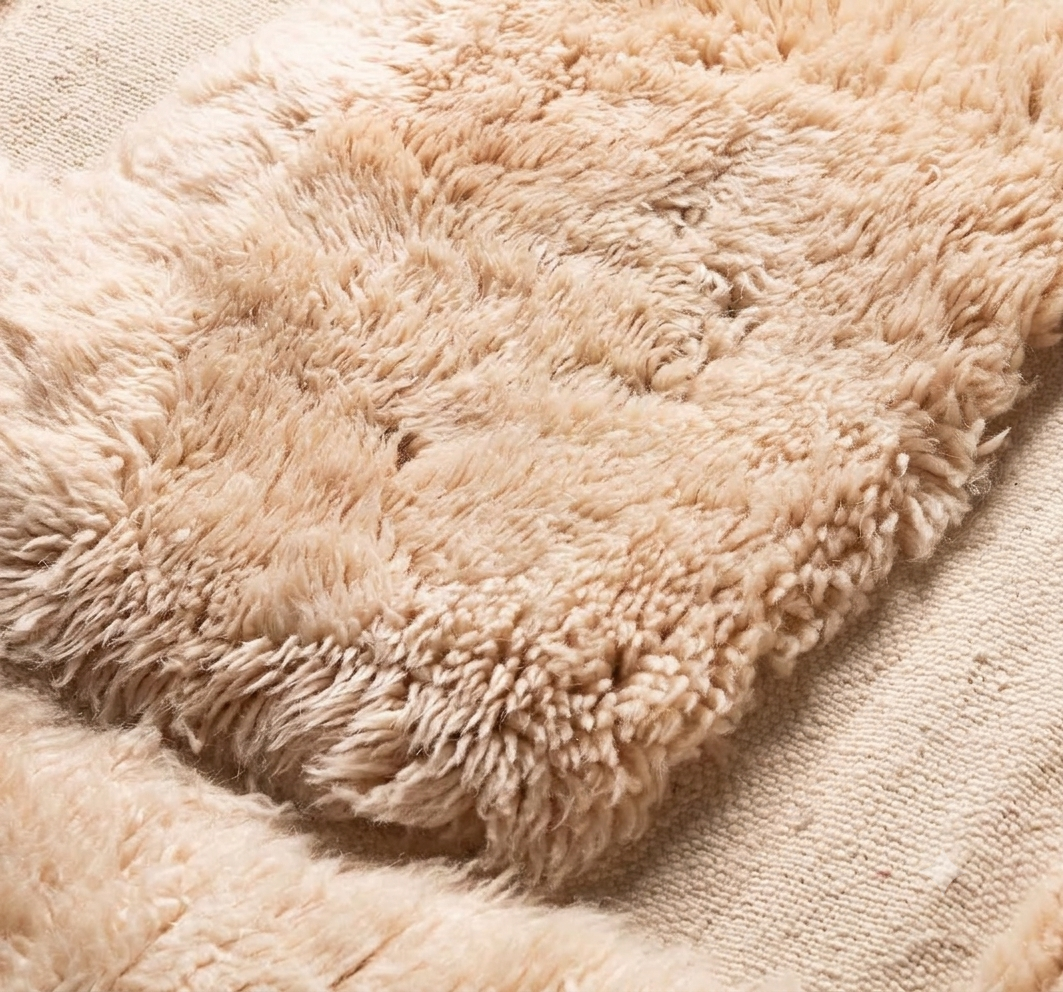 A close-up of a Beni Ourain Moroccan rug in sand wool 118 x 79 in with raised pile blocks on a flatweave ground